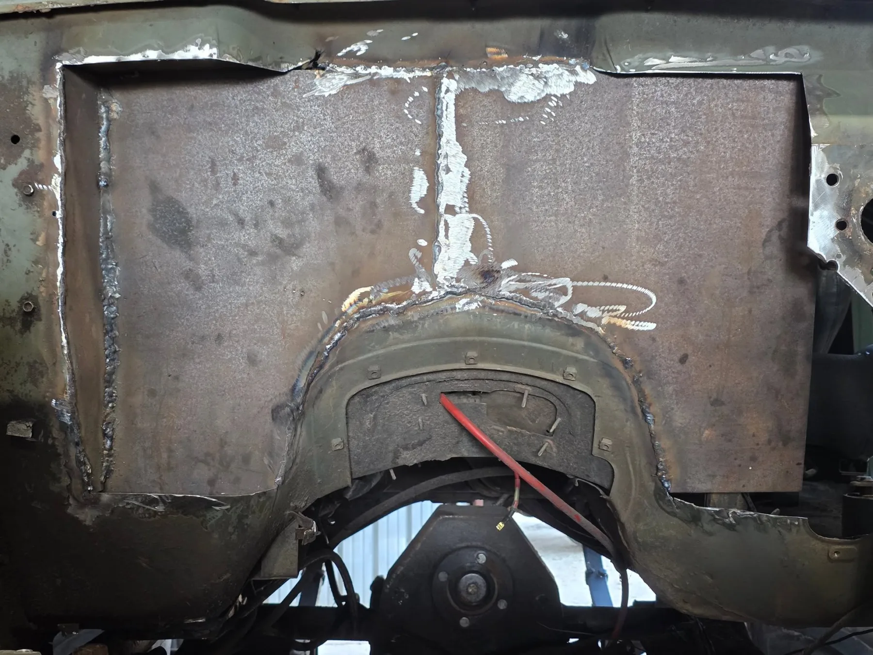 Close-up of welded steel panels around Sarge's wheel well during a rebuild